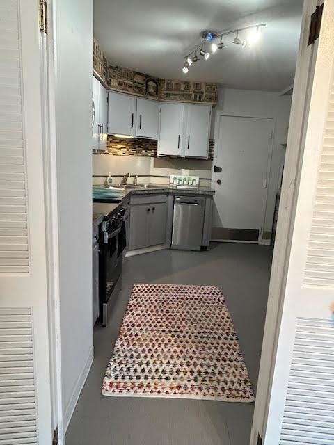 kitchen featuring sink, gray cabinetry, concrete floors, stainless steel dishwasher, and range