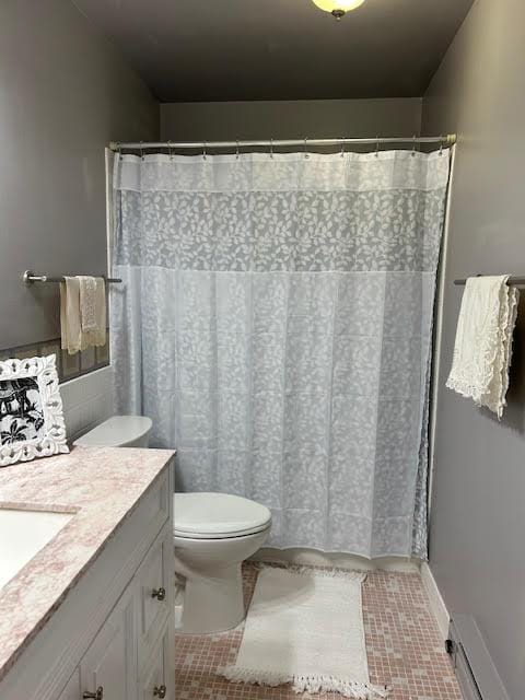 bathroom featuring curtained shower, vanity, a baseboard heating unit, toilet, and tile patterned floors