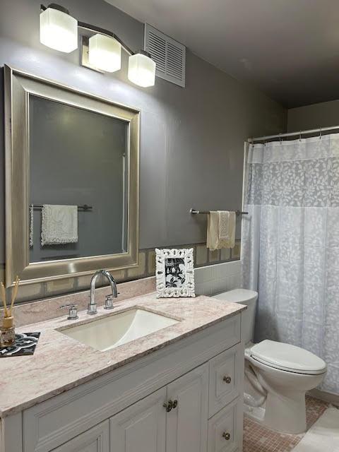 bathroom featuring vanity, tile walls, and toilet