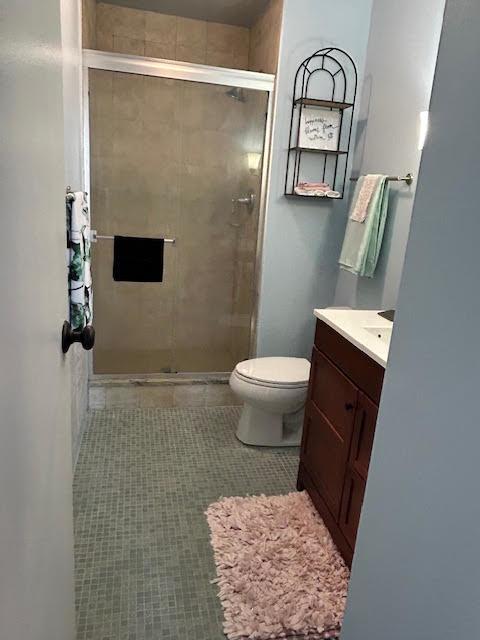 bathroom featuring vanity, an enclosed shower, tile patterned flooring, and toilet