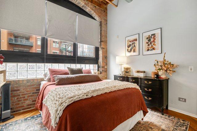 bedroom featuring wood-type flooring and brick wall