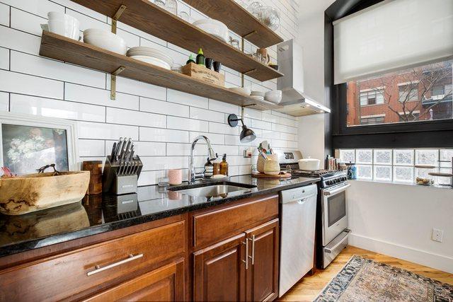 kitchen featuring stainless steel gas range oven, dark stone counters, sink, light hardwood / wood-style flooring, and dishwasher