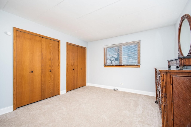 bedroom with light carpet and two closets