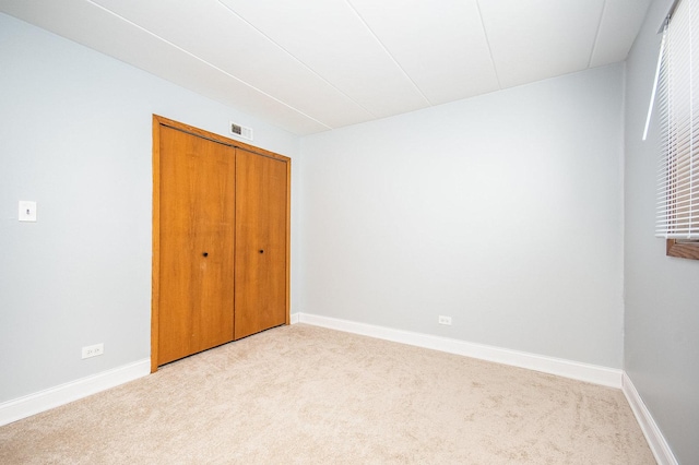 unfurnished bedroom with a closet and light carpet