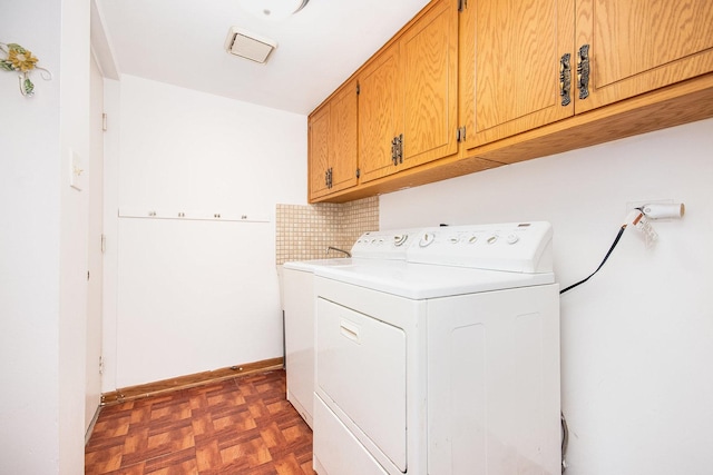 clothes washing area featuring dark parquet floors, cabinets, and washer and dryer