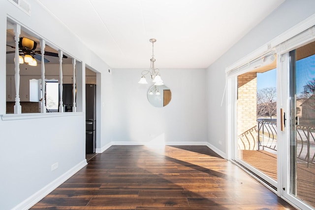 unfurnished dining area featuring ceiling fan with notable chandelier, a wealth of natural light, and dark hardwood / wood-style flooring