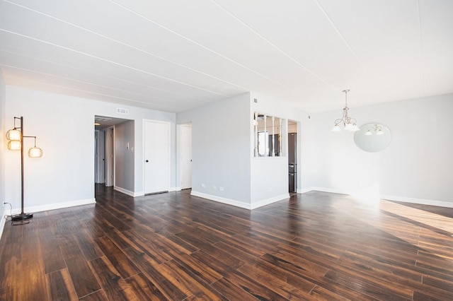 spare room featuring dark hardwood / wood-style flooring and a notable chandelier