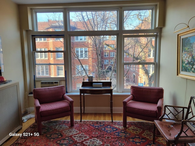 sitting room with radiator heating unit, light hardwood / wood-style floors, and cooling unit