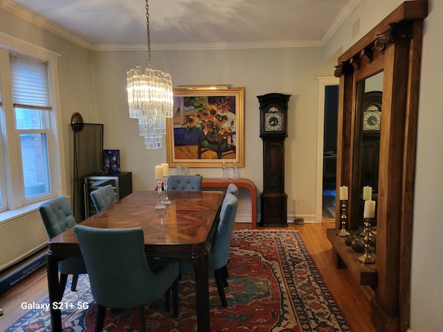 dining area with hardwood / wood-style flooring, crown molding, and a notable chandelier