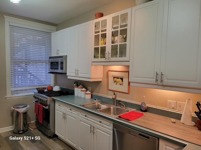 kitchen with appliances with stainless steel finishes, white cabinetry, and sink