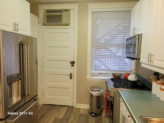 kitchen featuring white cabinetry, high quality appliances, hardwood / wood-style flooring, and an AC wall unit