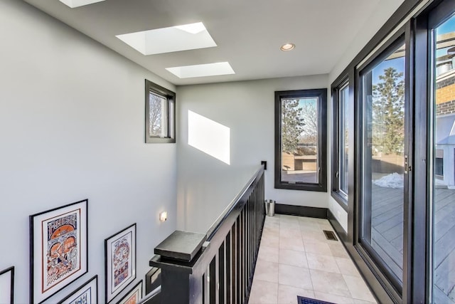 hallway featuring light tile patterned floors and a skylight