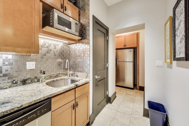 kitchen featuring light stone counters, stainless steel appliances, sink, and tasteful backsplash