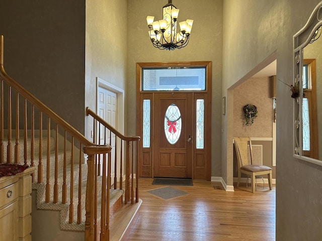 entrance foyer featuring a high ceiling, light wood-type flooring, and an inviting chandelier