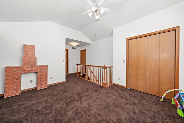 interior space featuring vaulted ceiling, dark colored carpet, and ceiling fan