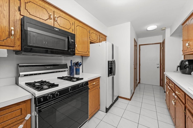 kitchen with light tile patterned floors, gas range oven, and white fridge with ice dispenser