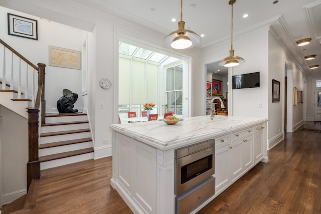 kitchen featuring light stone countertops, a kitchen island with sink, crown molding, sink, and white cabinetry