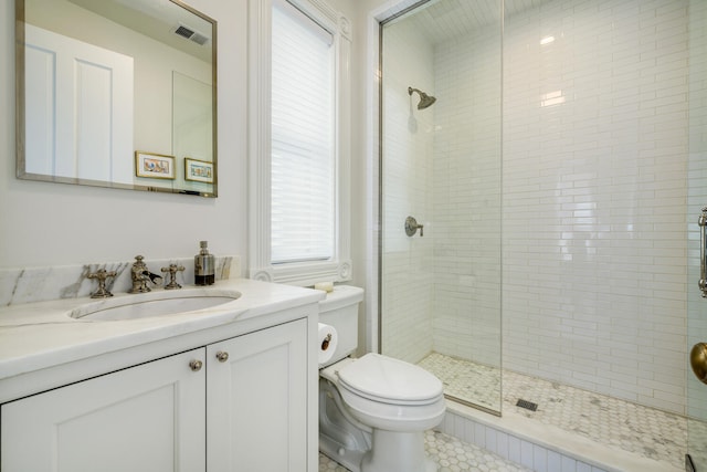 bathroom with vanity, toilet, tile patterned flooring, and tiled shower