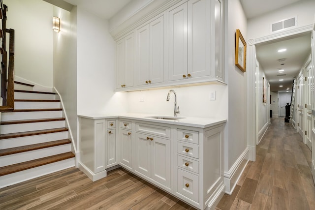 bar featuring white cabinetry, sink, and hardwood / wood-style floors