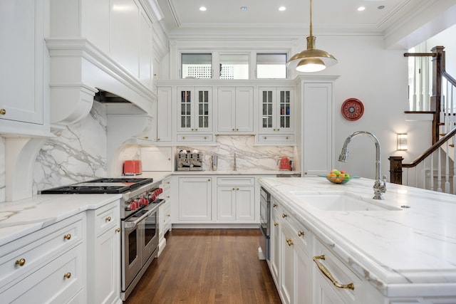 kitchen featuring backsplash, white cabinets, range with two ovens, sink, and light stone counters