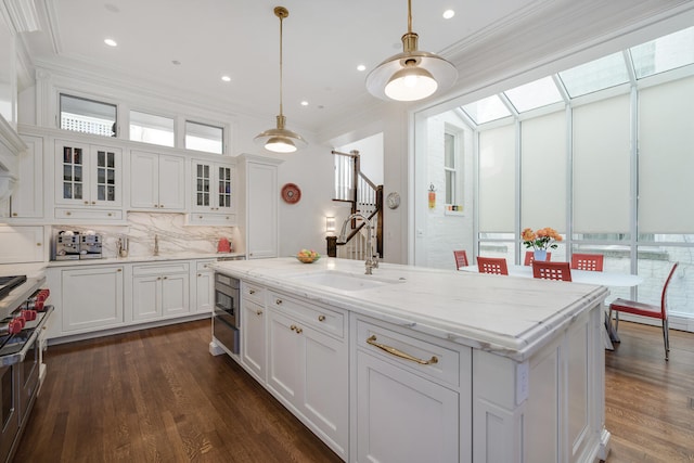 kitchen featuring white cabinets, built in microwave, sink, and an island with sink