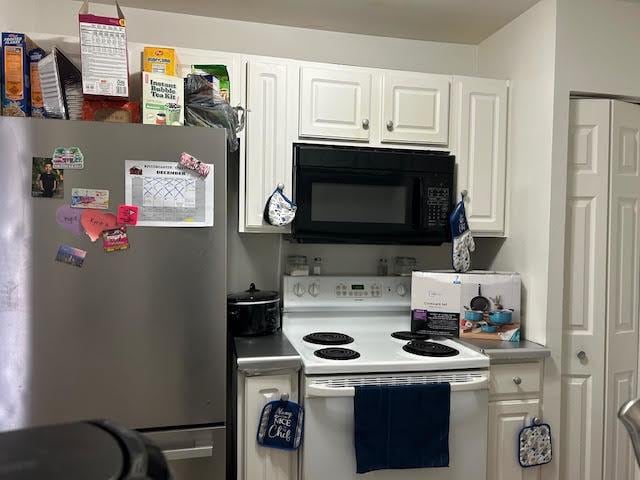 kitchen with stainless steel refrigerator, white cabinetry, and white range with electric cooktop