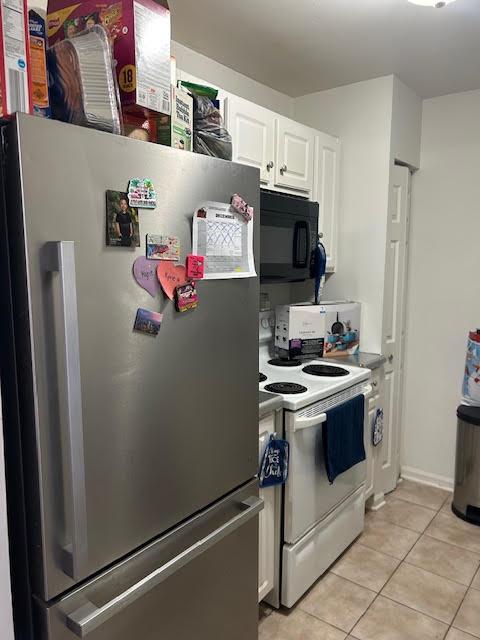 kitchen with white cabinets, white electric range, light tile patterned floors, and stainless steel refrigerator