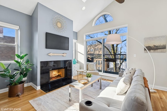 living room featuring hardwood / wood-style flooring, high vaulted ceiling, and a tiled fireplace