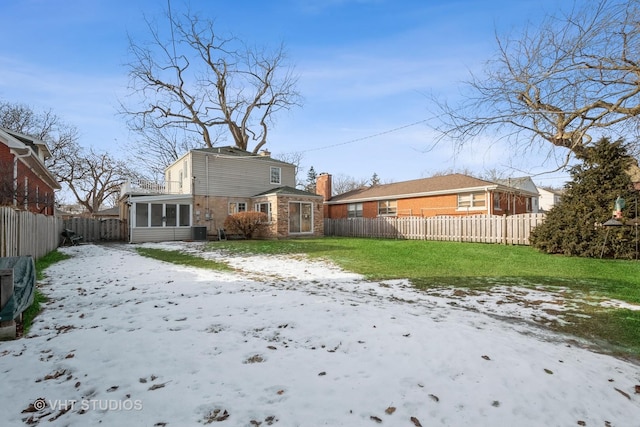 snow covered house featuring a yard and a sunroom