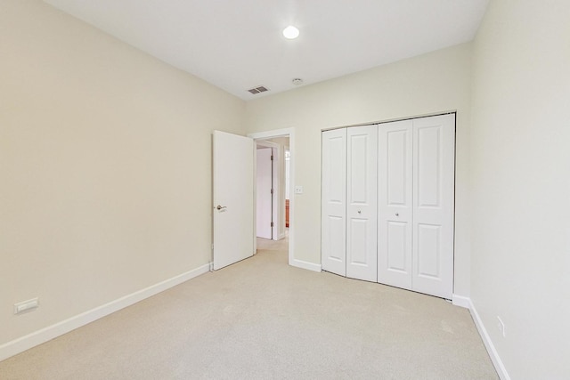 unfurnished bedroom with light carpet and a closet