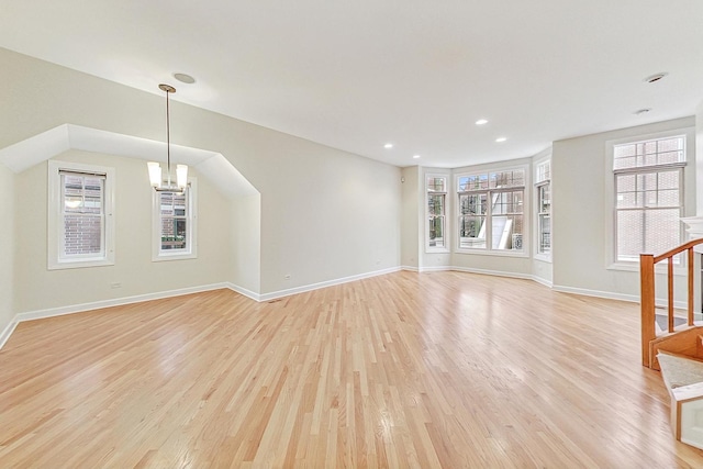 unfurnished living room with a chandelier and light wood-type flooring