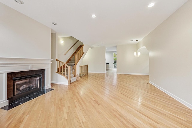 unfurnished living room featuring a fireplace, a chandelier, and light hardwood / wood-style flooring