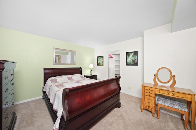 bedroom with light colored carpet and a spacious closet