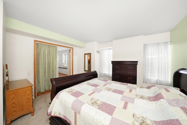 bedroom featuring light colored carpet and multiple windows