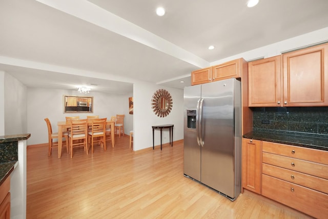 kitchen with stainless steel fridge, light hardwood / wood-style floors, backsplash, and dark stone counters