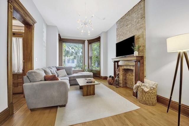 living room featuring a chandelier, light wood-type flooring, and a stone fireplace