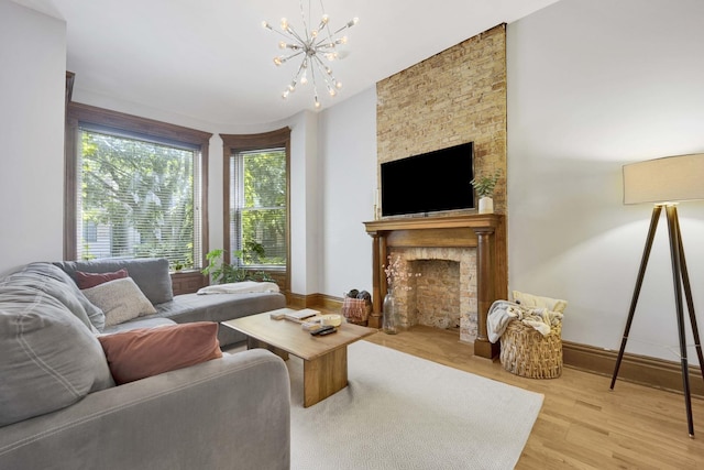 living room with a fireplace, a chandelier, and light wood-type flooring