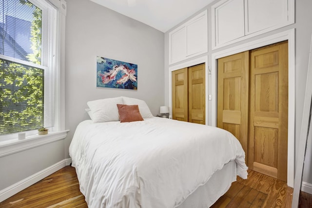 bedroom featuring hardwood / wood-style floors and multiple closets