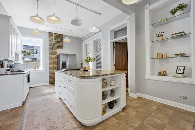 kitchen featuring dark stone counters, white cabinets, sink, decorative light fixtures, and stainless steel fridge with ice dispenser