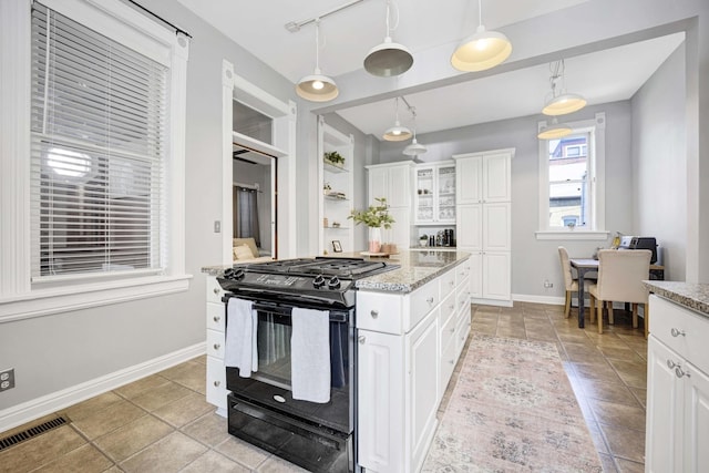 kitchen with light stone countertops, black gas range oven, light tile patterned floors, decorative light fixtures, and white cabinetry