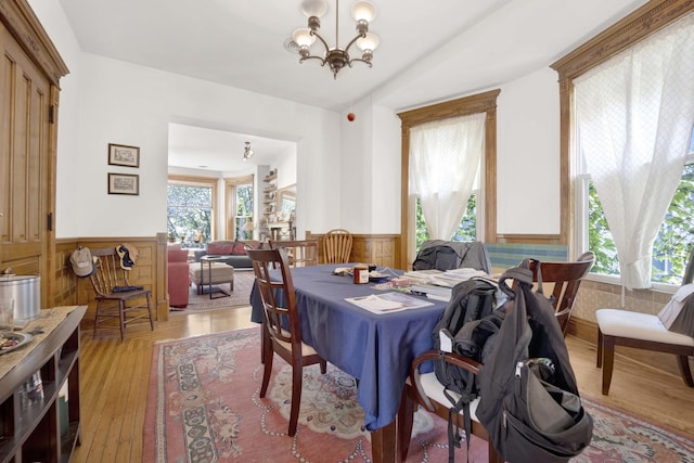 dining area with a wealth of natural light, light hardwood / wood-style flooring, and a notable chandelier