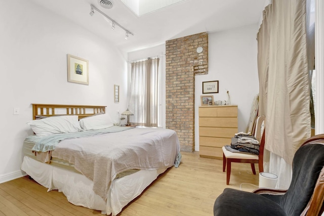 bedroom with a skylight, light hardwood / wood-style flooring, and rail lighting