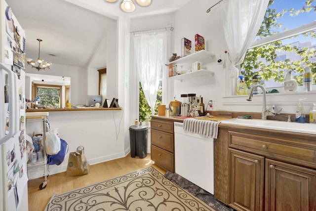 kitchen with a wealth of natural light, light hardwood / wood-style flooring, decorative light fixtures, and an inviting chandelier