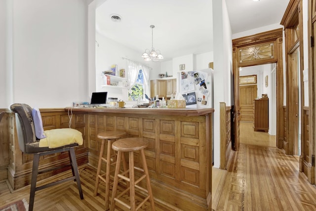 bar with light hardwood / wood-style flooring, an inviting chandelier, and hanging light fixtures