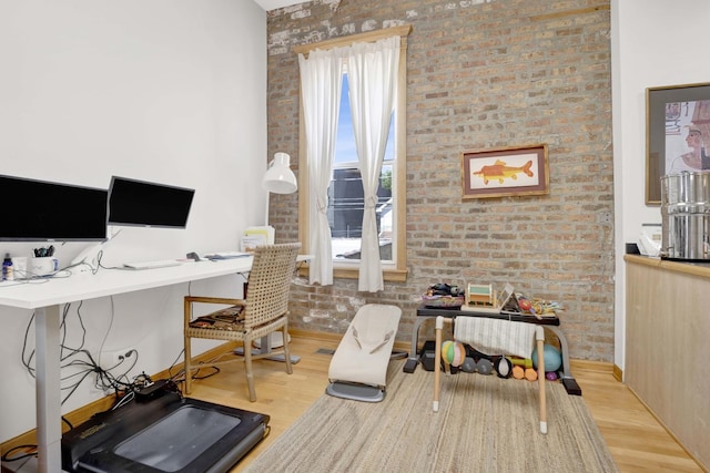 office space featuring light wood-type flooring and brick wall