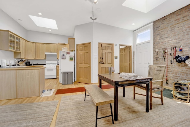 dining area with a skylight, sink, and light wood-type flooring