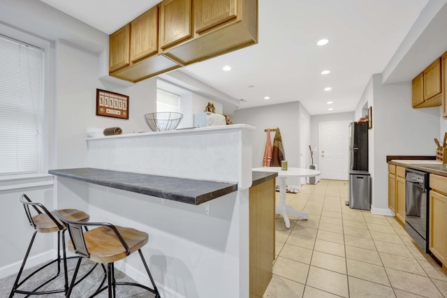 kitchen with a kitchen bar, kitchen peninsula, black dishwasher, and light tile patterned floors