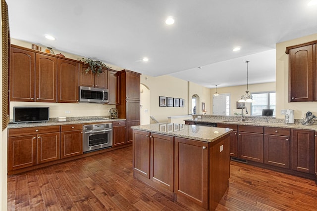 kitchen with sink, dark hardwood / wood-style floors, kitchen peninsula, decorative light fixtures, and appliances with stainless steel finishes