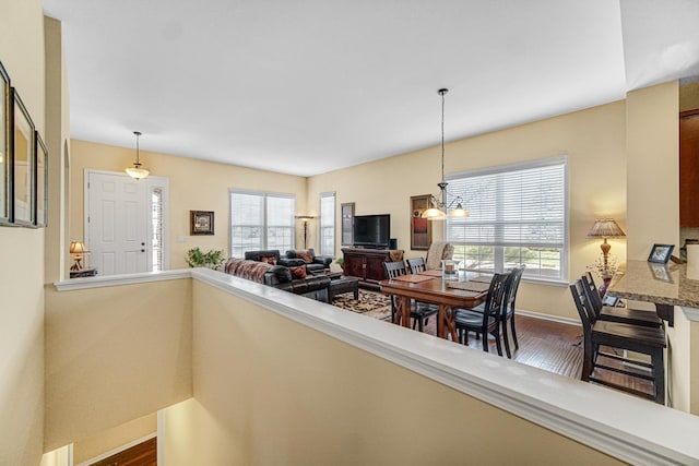 interior space featuring a wealth of natural light, dark wood-type flooring, and an inviting chandelier