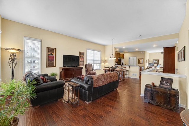 living room with ceiling fan, dark wood-type flooring, and a healthy amount of sunlight